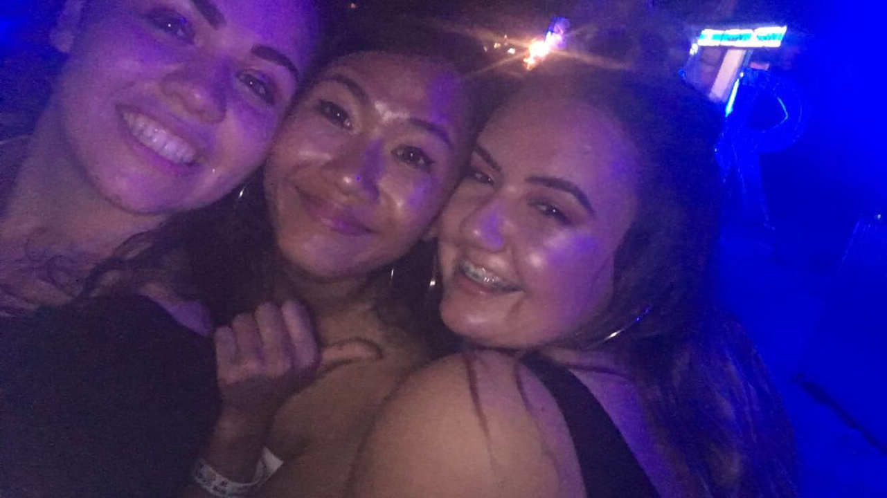 Three friends taking a selfie at a night event.