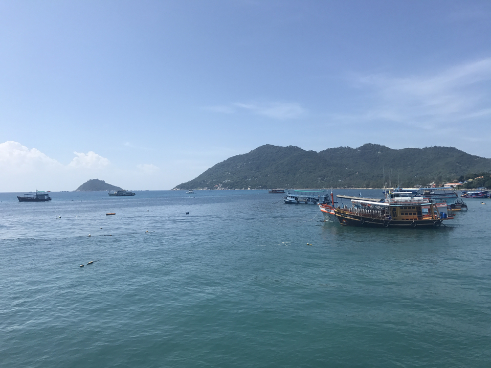 Boats on the ocean with hilly islands in the distance.