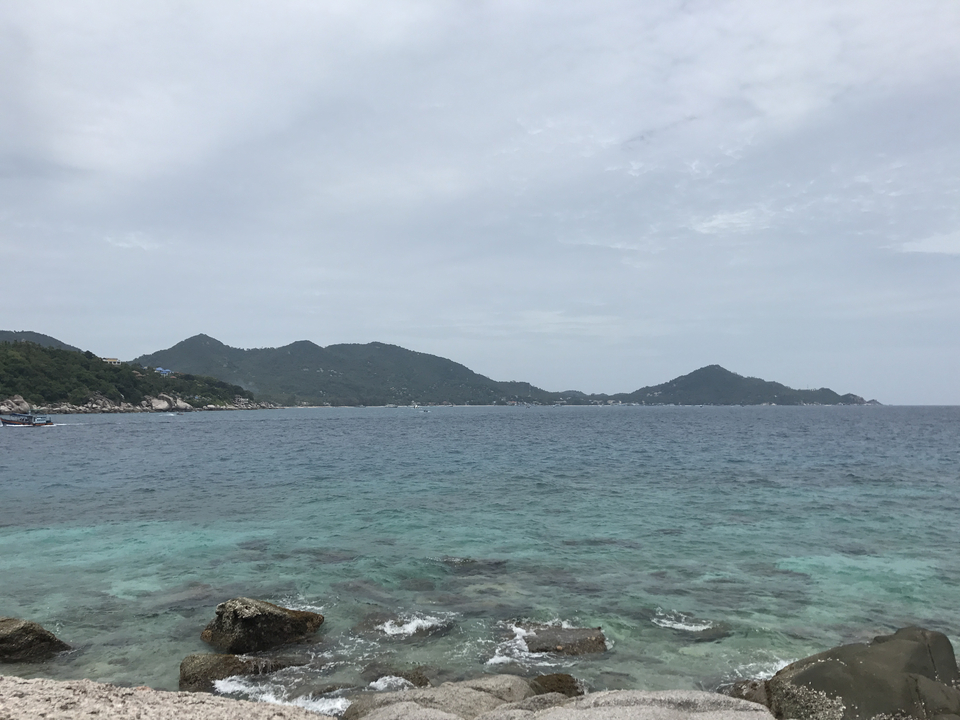 View of the ocean with mountains under a cloudy sky.