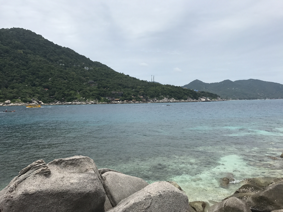 Ocean and hills with rocky coastline under a cloudy sky.