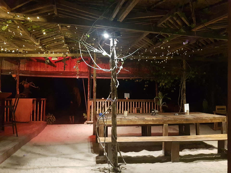 Empty wooden seating area with fairy lights at night.
