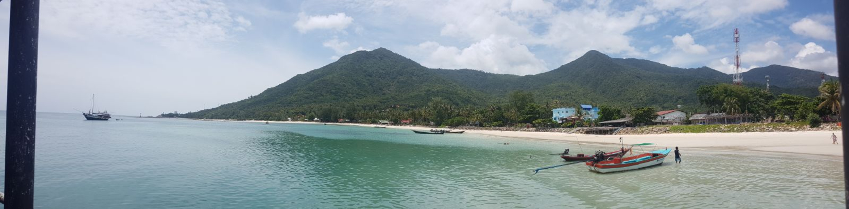 Sea view of a beach with mountains and boats.