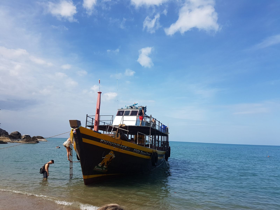 Person walking onto a boat docked by the sea.