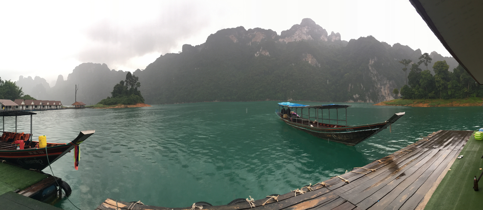 Traditional boat on a turquoise lake with misty mountains.