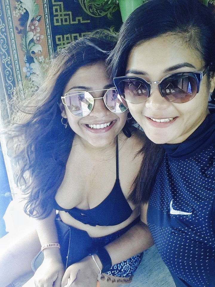 Close-up of two women wearing sunglasses and smiling.