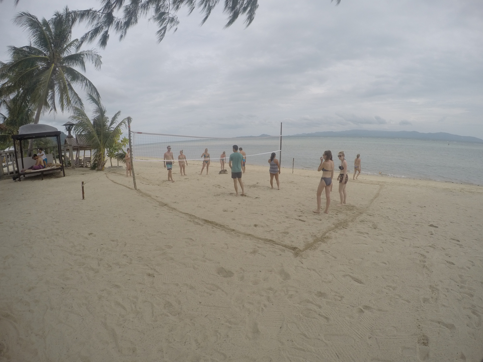 People playing beach volleyball near the ocean.