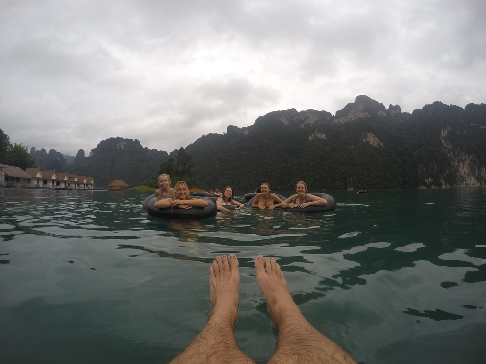 Group of people floating on a lake with mountainous surroundings.