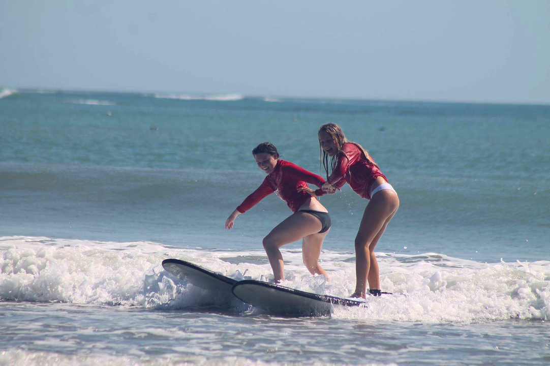 Two people surfing in the ocean.
