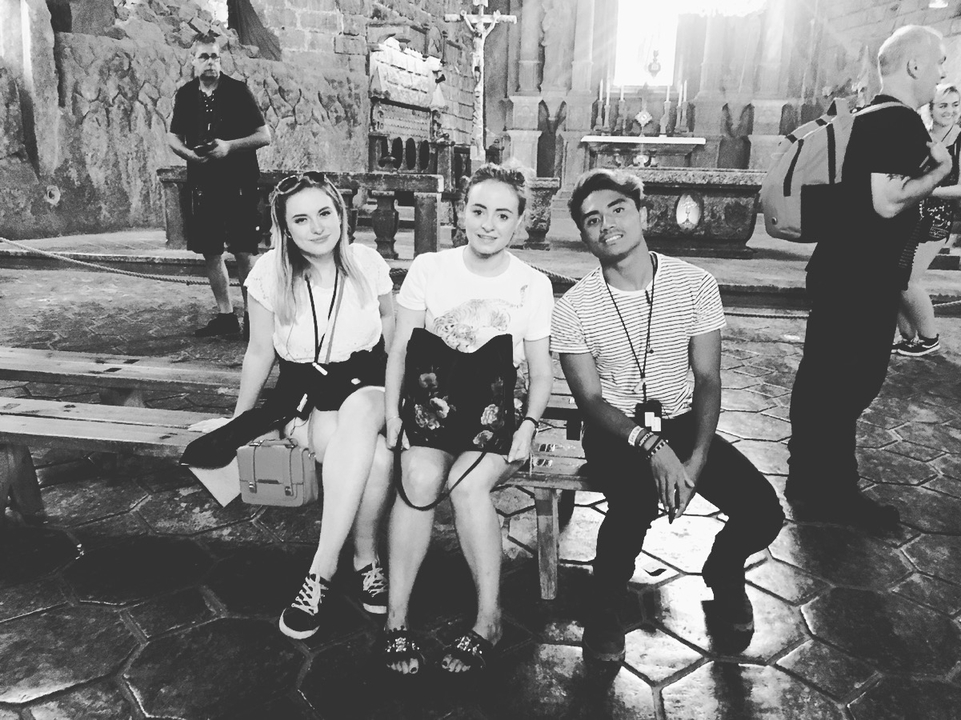 A group sitting on wooden benches in an indoor setting.