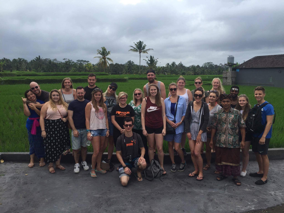 Group of people posing in a green field.