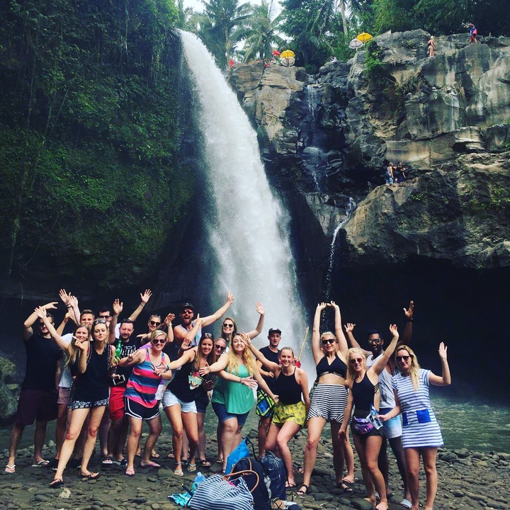 Group of people in front of a waterfall.