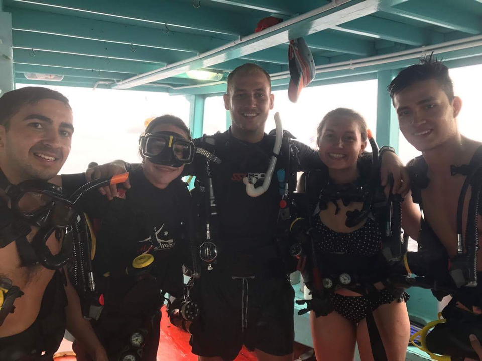Group of scuba divers posing for a photo on a boat.