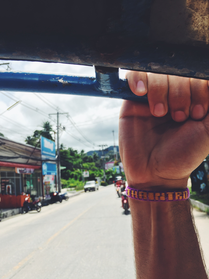 Hand holding a blue metal bar with a road and mountains in the background.