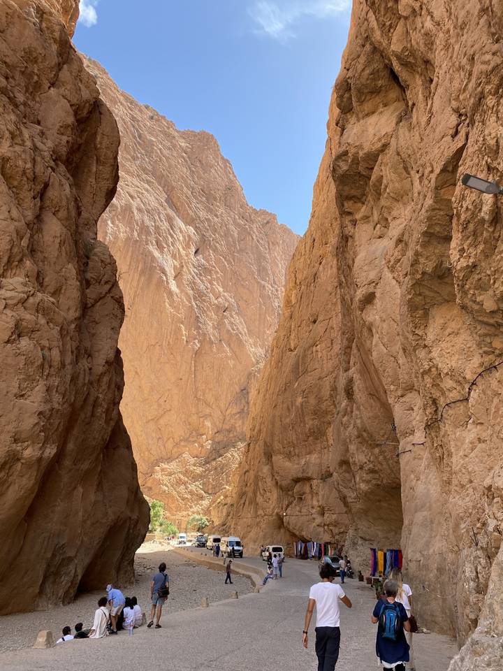Todra Gorge with visitors walking and cars parked.