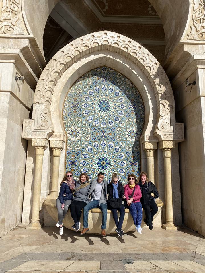 Group of people posing in front of an ornate architectural design.