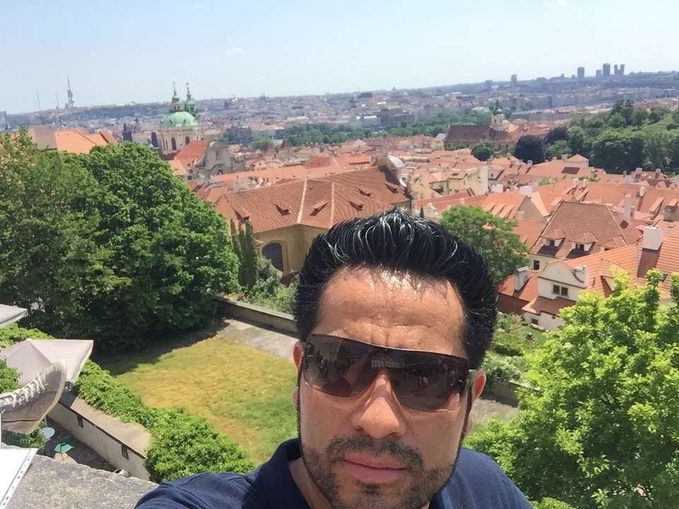 Person taking a selfie with panoramic city view in the background.