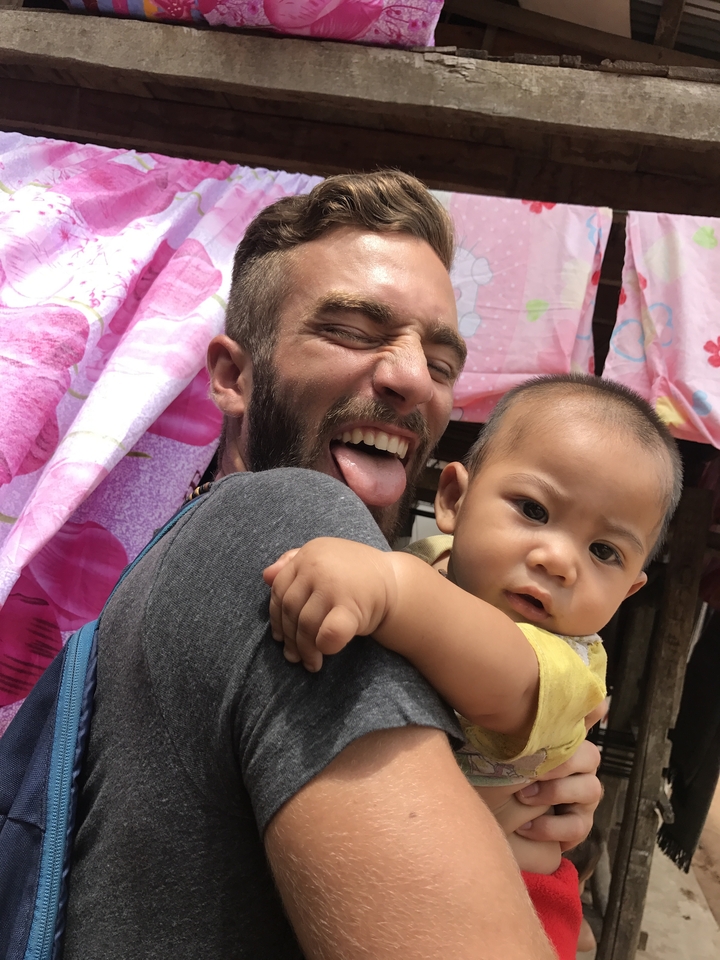 A man and a baby posing humorously with colorful cloth in the background.