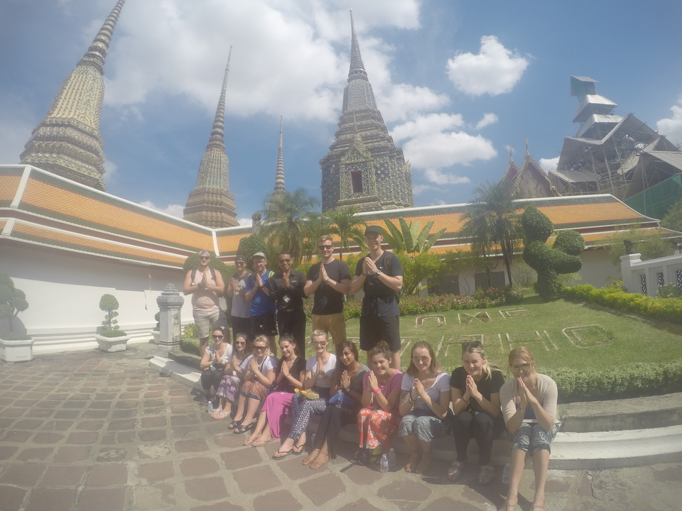 Group posing in front of a temple with greenery.