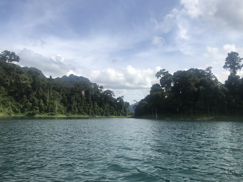 A serene water body flanked by dense green forests and hills.