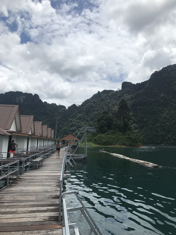 Wooden lake houses with lush green mountains in the background.