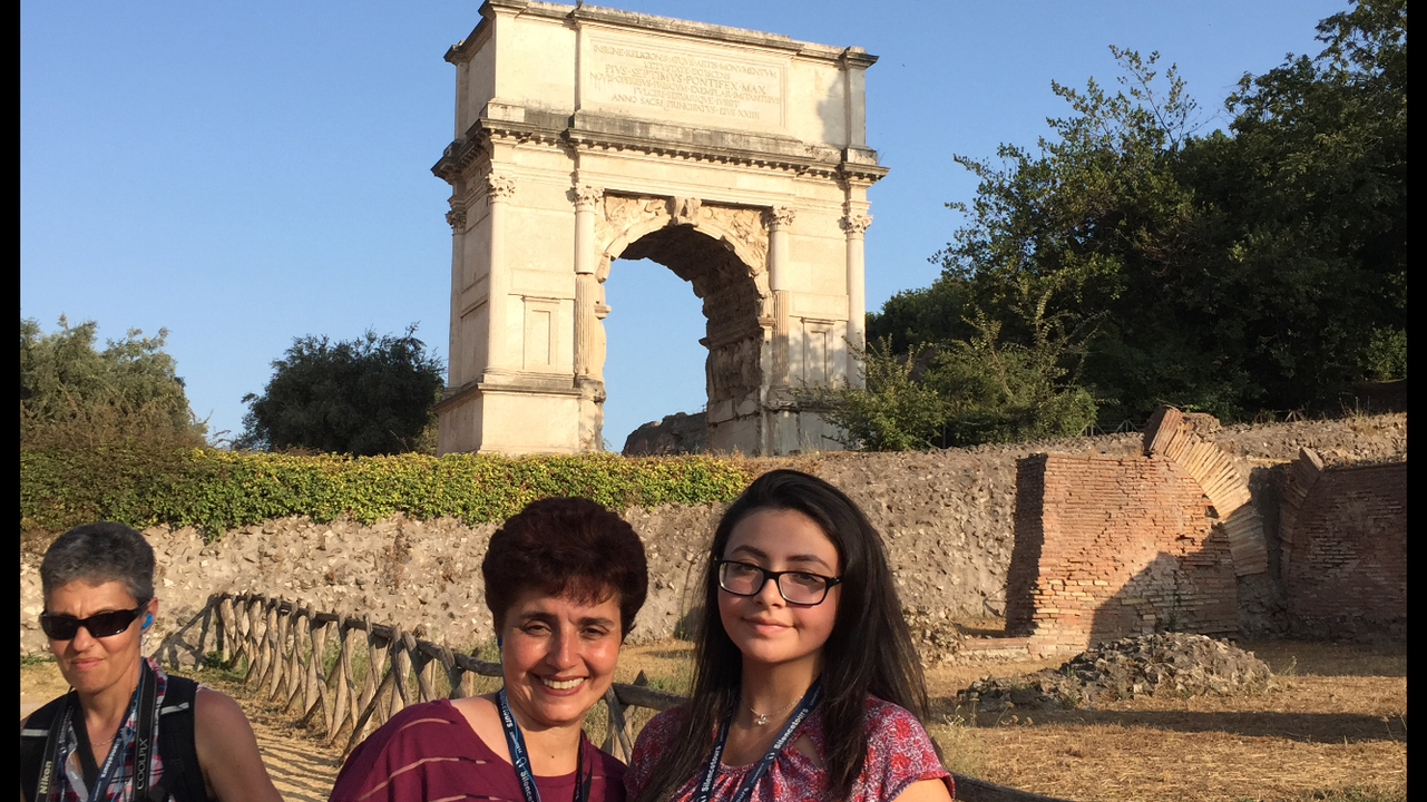 Two people near an ancient Roman arch.
