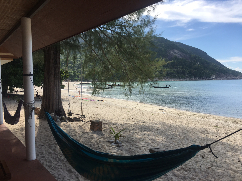Sandy beach with hammocks and clear water views.