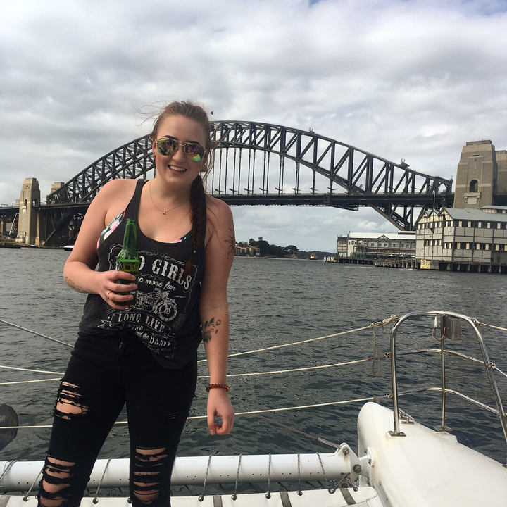 Person holding a green bottle with the Sydney Harbour Bridge in the background.
