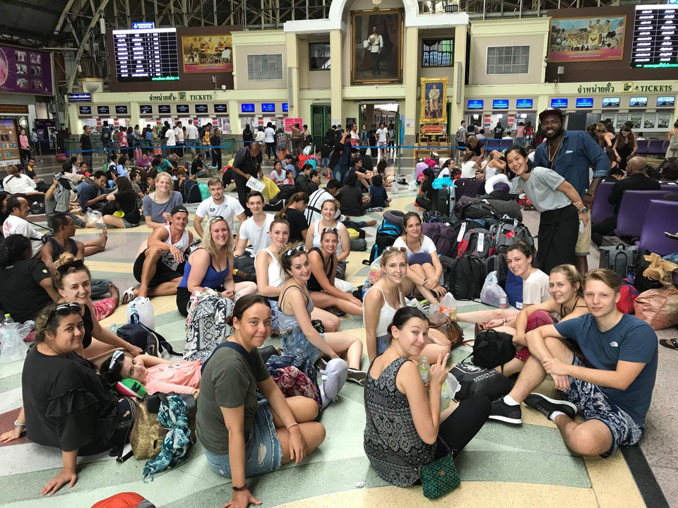 Large group of travelers with backpacks waiting in a terminal.
