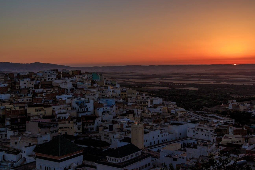 A sunset over a hillside covered in closely packed buildings.