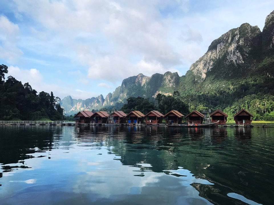 Floating bungalows on a serene lake with mountains in the backdrop.