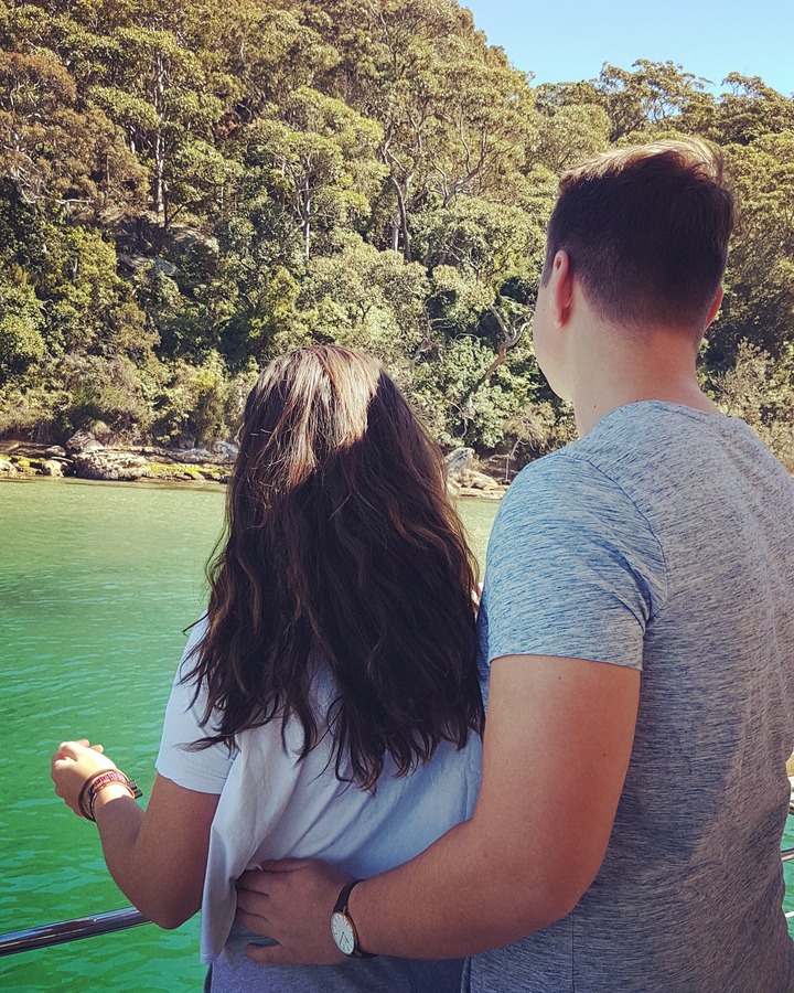 Two people standing in front of a water body.