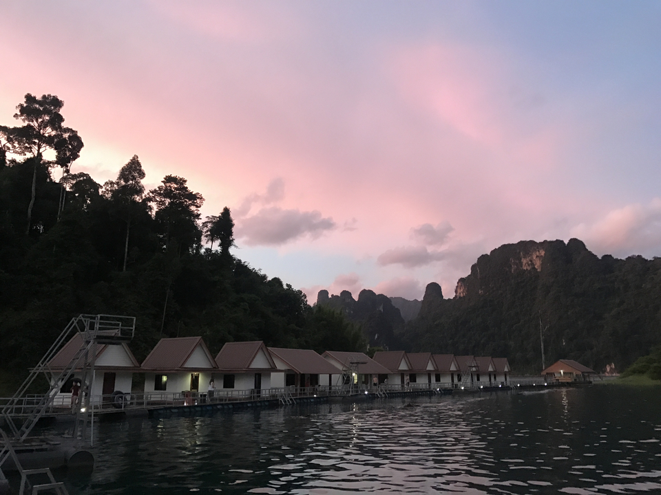 Scenic sunset view of floating bungalows in front of cliffs.