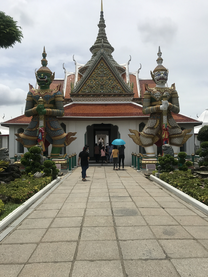 Tourists entering a temple with large statues at the entrance.