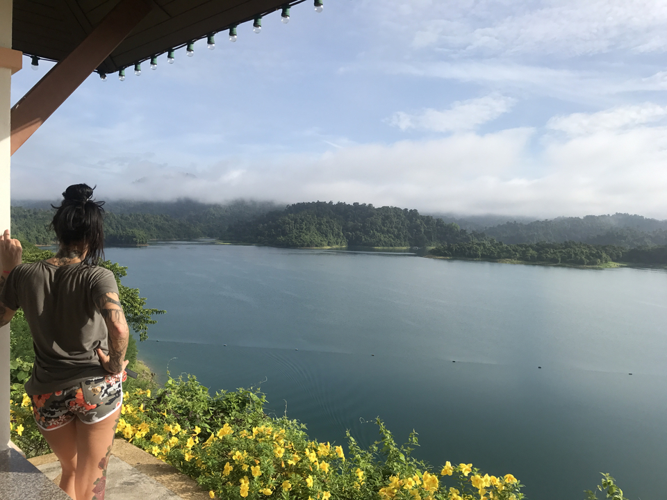 Person looking over a lake with lush hills.