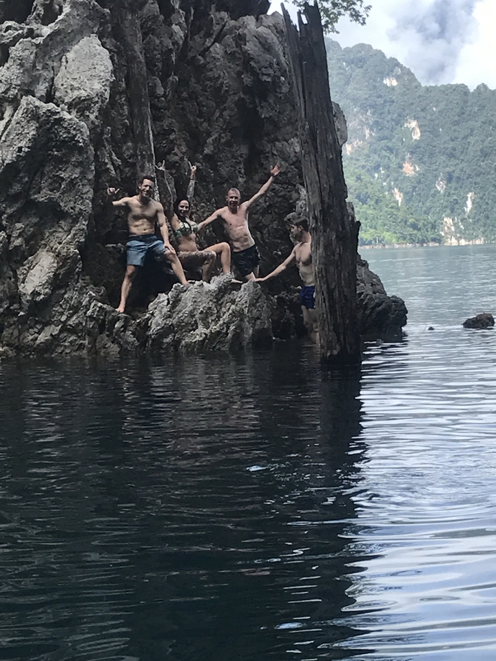 Group of people posing on rocks near a water body.
