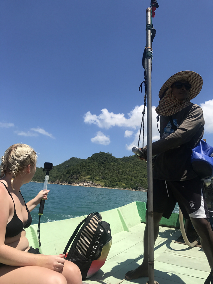 Boating view with two people and a green hill in the background.