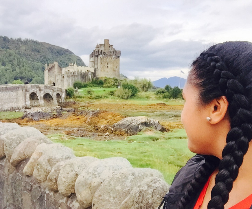 Person looking at Eilean Donan Castle with a stone bridge.