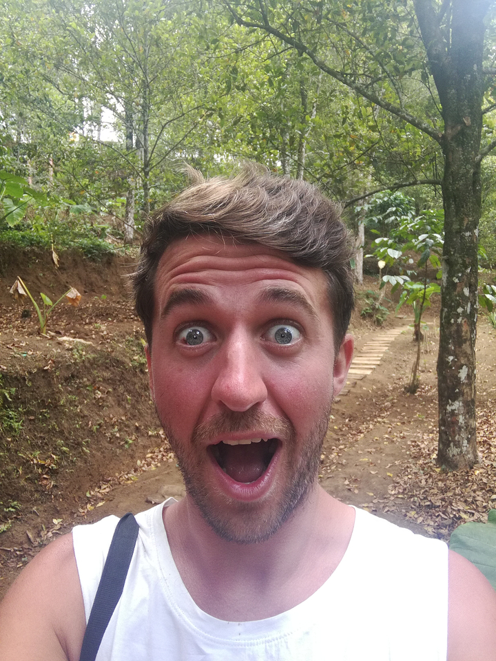 Close-up of a man looking surprised in a forest setting.