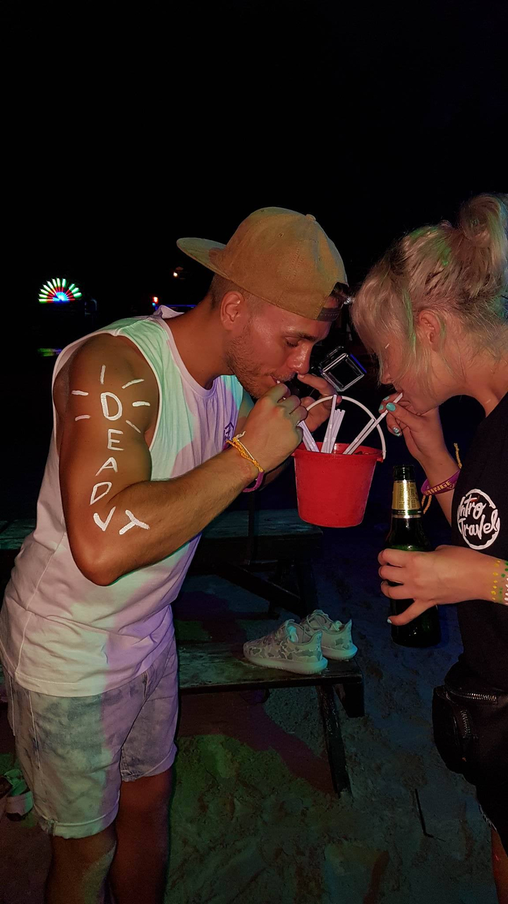 Two people sharing a drink at a night beach party.