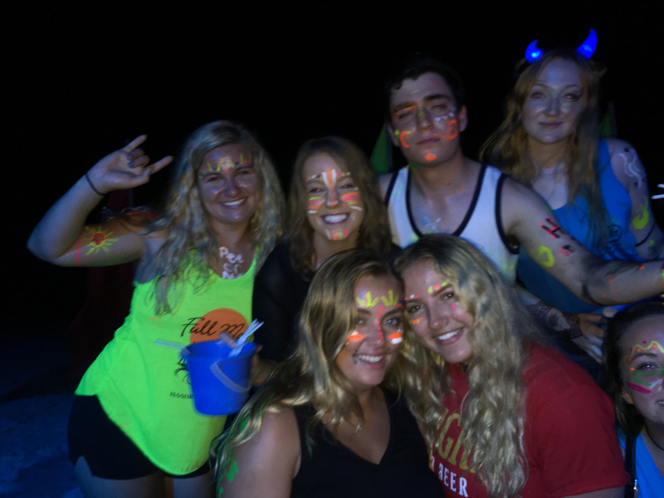 Group of people with neon face paint at night.