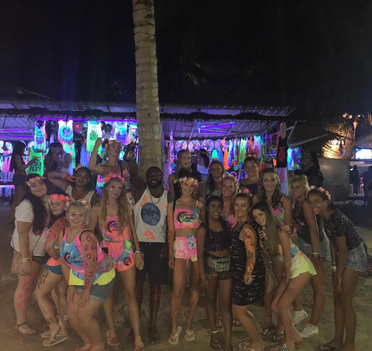 Large group of people in glow party attire at night.