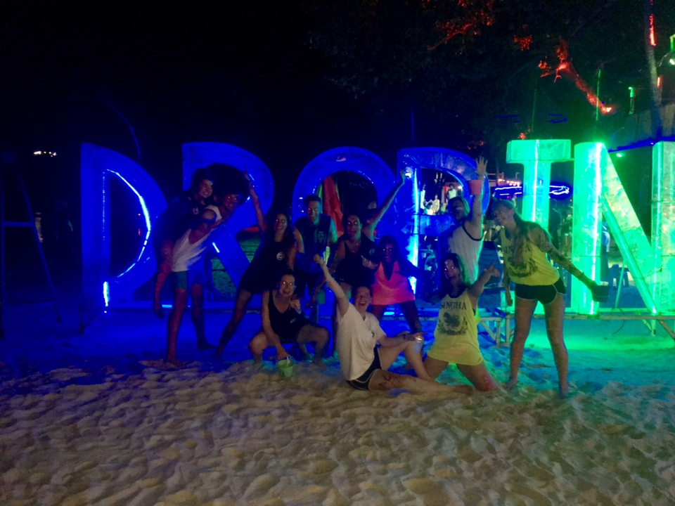 Group of people posing with illuminated signs at night.