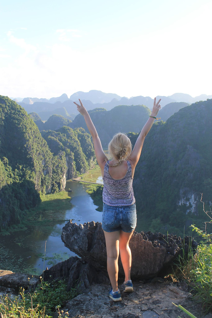 Person with arms raised in front of a scenic valley.