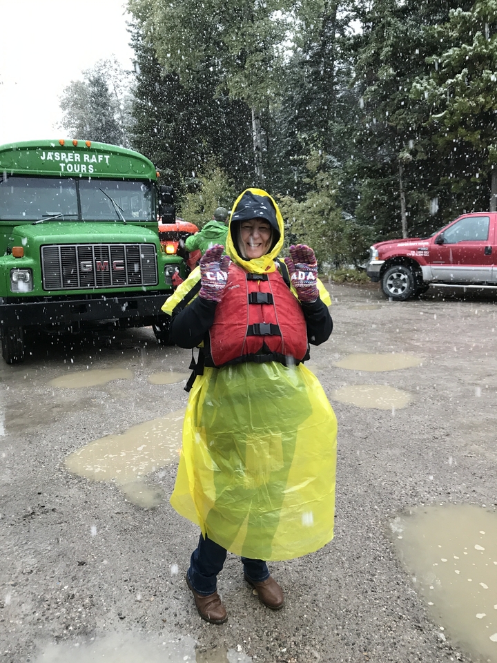 Personne en tenue de pluie souriant dans un environnement pluvieux.