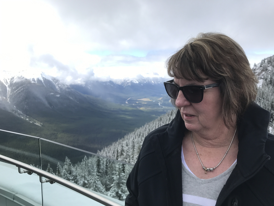 Femme avec des lunettes de soleil regardant un paysage montagneux.