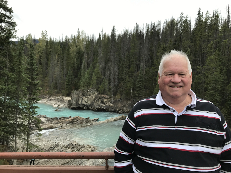 Homme devant une rivière turquoise dans une forêt.