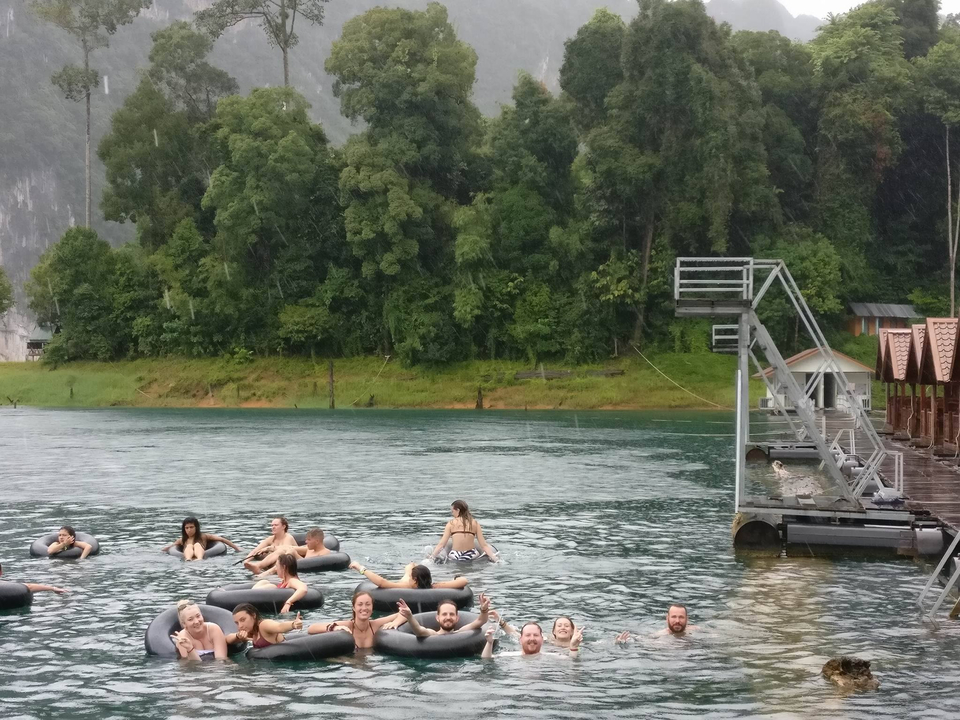 People swimming and relaxing in a lake surrounded by forest.