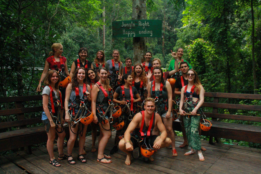 Un groupe de personnes portant des harnais et des casques dans une forêt.