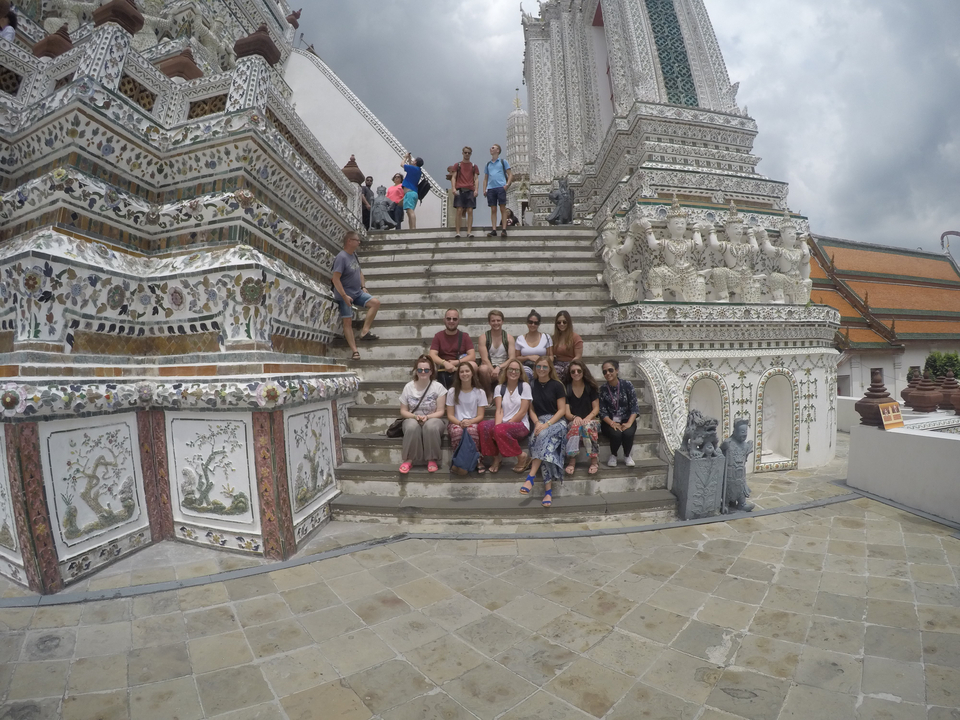 A group of people sitting on steps in front of an ornate building.