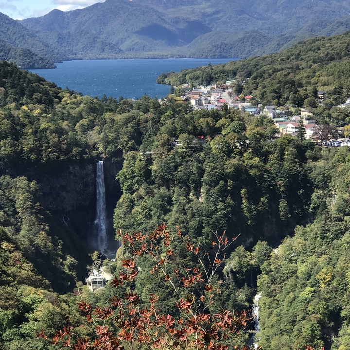 Cascade dans un paysage verdoyant avec une ville au loin.
